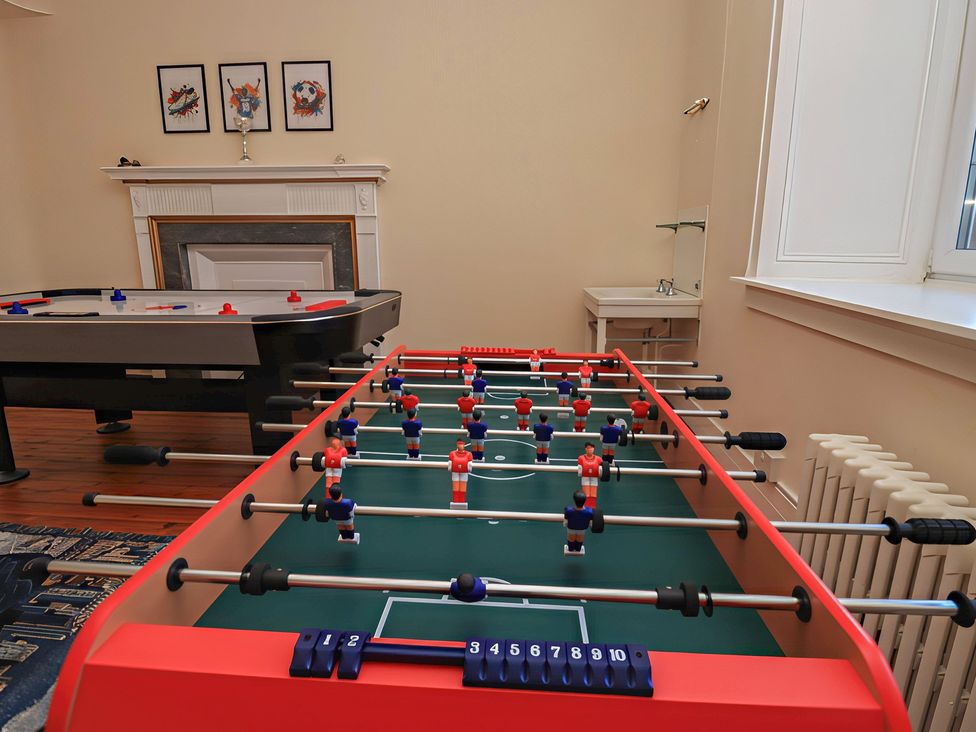 A foosball table and air hockey table in a game room at Auchentroig House Buchlyvie