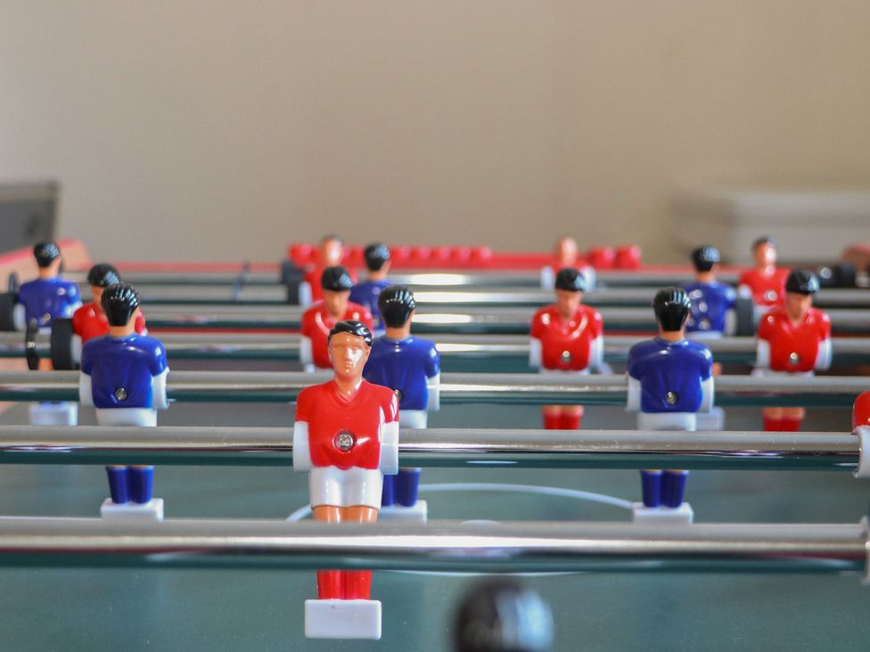 A foosball table with red and blue players in a game room at Auchentroig House Buchlyvie