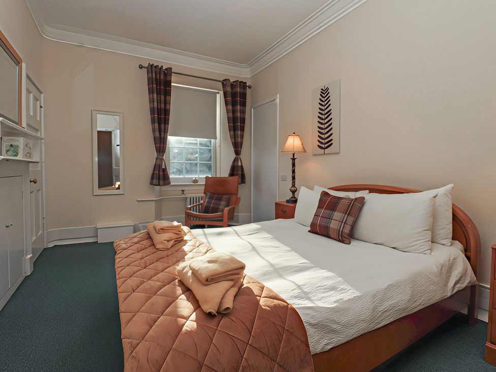 A bedroom with a bed and a chair at Auchentroig House in Buchlyvie