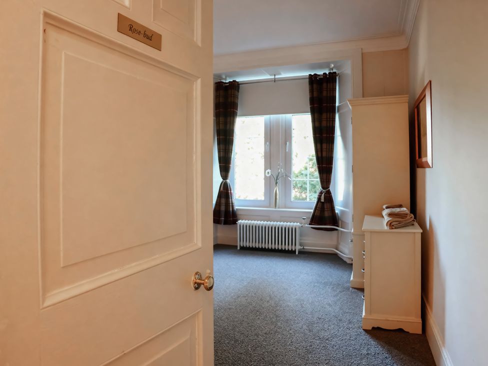 A bedroom with curtains and a radiator at Auchentroig House Buchlyvie