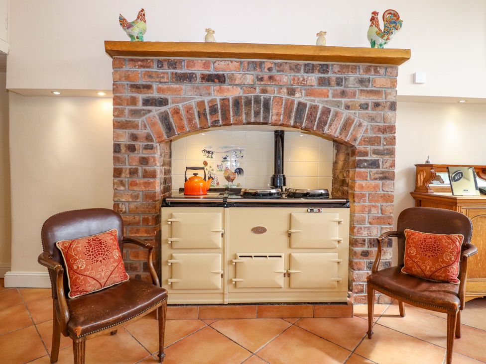 A kitchen with a stove and chairs at Rob Roy Apartment in Buchlyvie