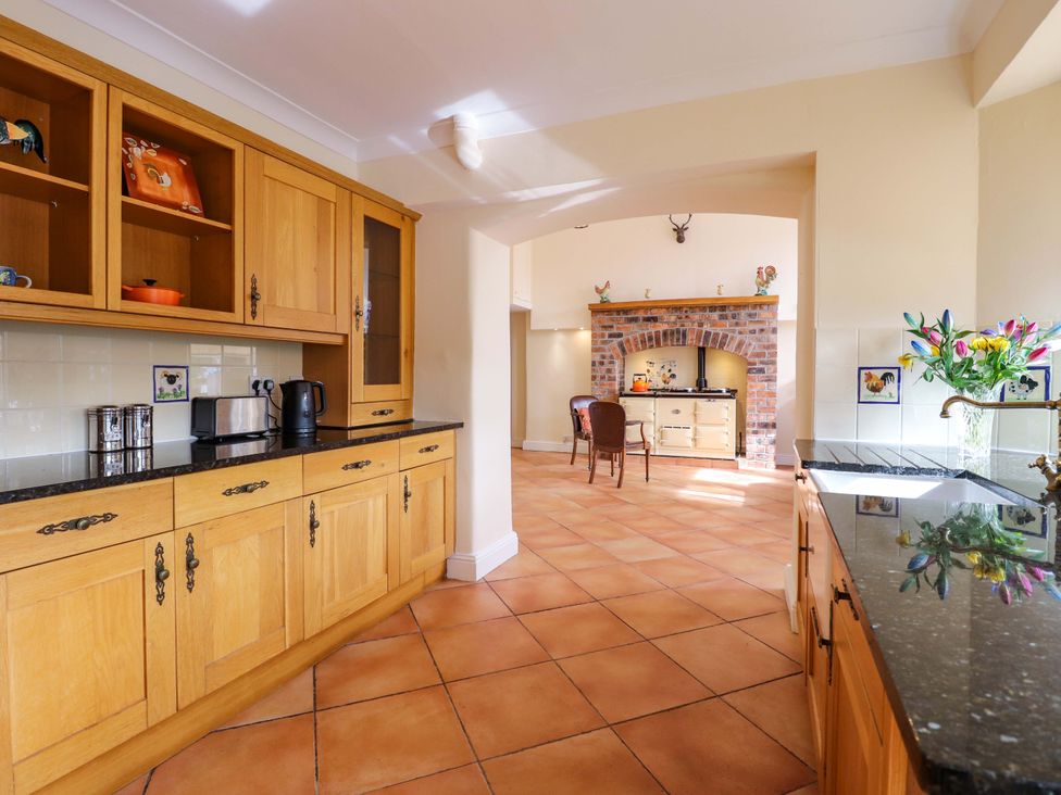 A kitchen with cabinets and a brick fireplace at Rob Roy Apartment in Buchlyvie
