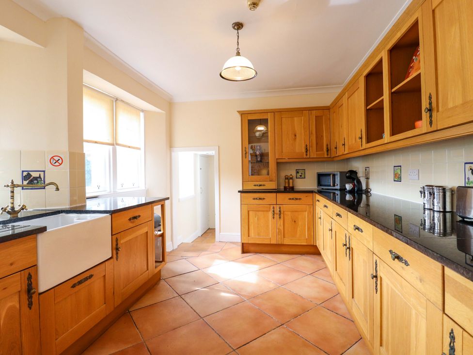A kitchen with wooden cabinets and a sink at Rob Roy Apartment in Buchlyvie
