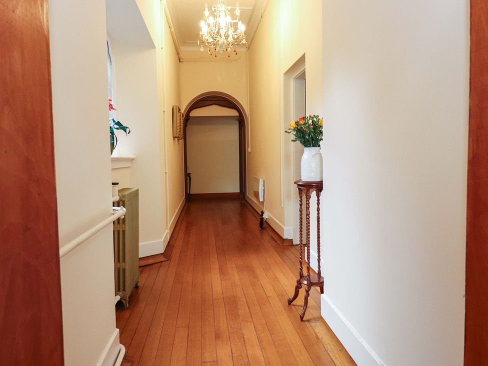 A hallway with a chandelier and a flower vase at Rob Roy Apartment in Buchlyvie