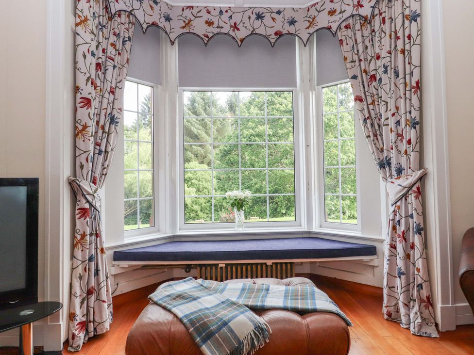 A window with curtains and a cushion in a living room at Rob Roy Apartment in Buchlyvie