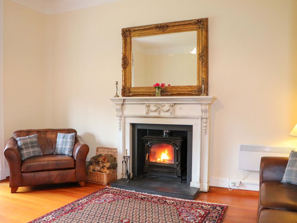 A living room with a fireplace and two chairs at Rob Roy Apartment in Buchlyvie