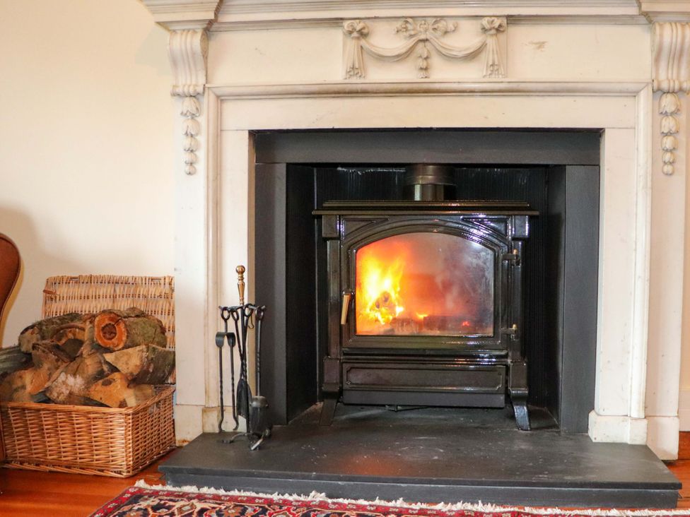 A fireplace with firewood and tools in a living room at Rob Roy Apartment in Buchlyvie