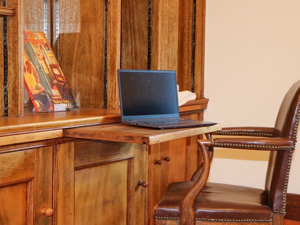 An office with a laptop on a desk and a chair at Rob Roy Apartment in Buchlyvie