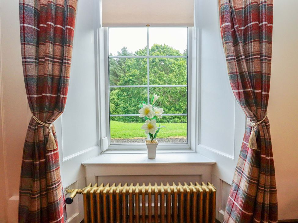 A window with curtains and a flower pot at Rob Roy Apartment in Buchlyvie