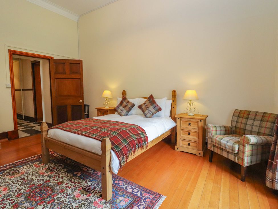A bedroom with a bed and a chair at Rob Roy Apartment in Buchlyvie