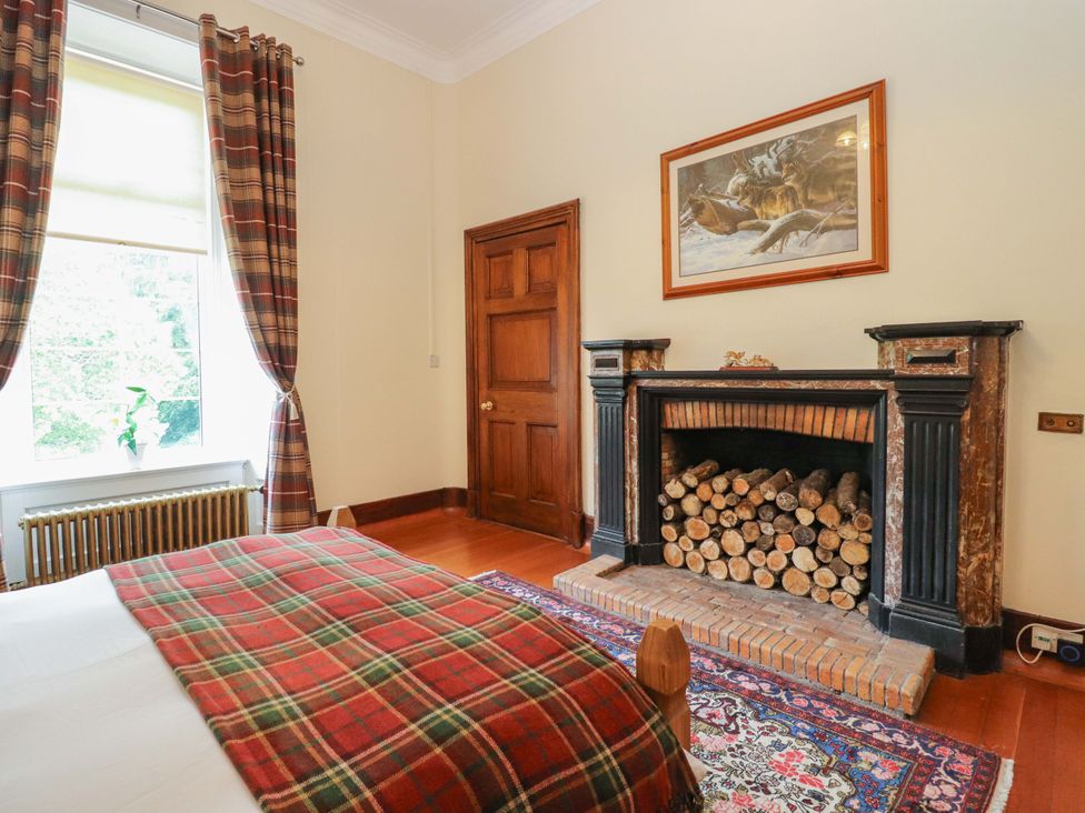 A bedroom with a bed and a fireplace at Rob Roy Apartment in Buchlyvie