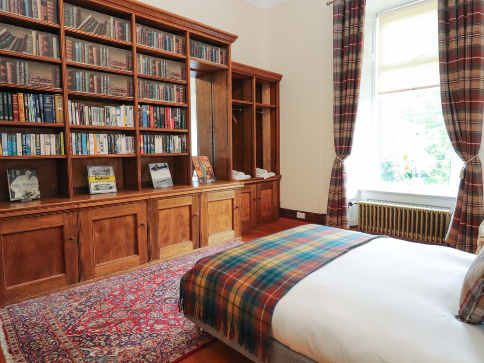 A bedroom with a bed and bookshelves at Rob Roy Apartment in Buchlyvie