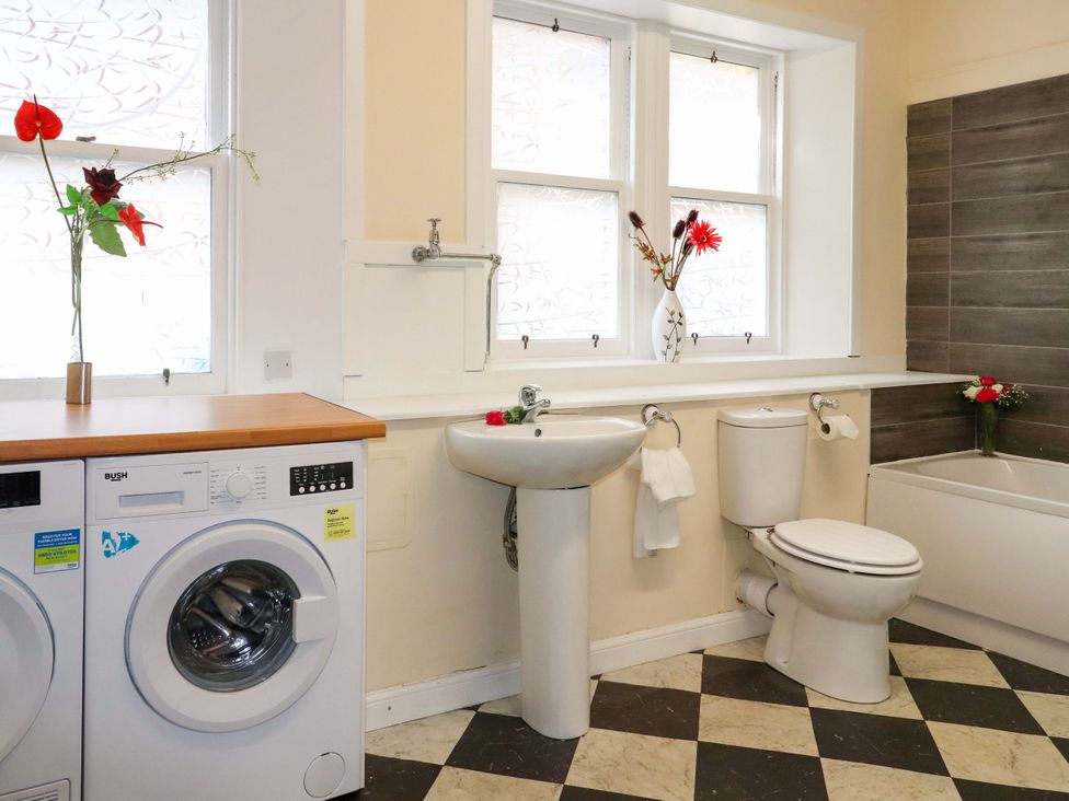 A bathroom with a washing machine, sink, toilet, and bathtub at Rob Roy Apartment in Buchlyvie