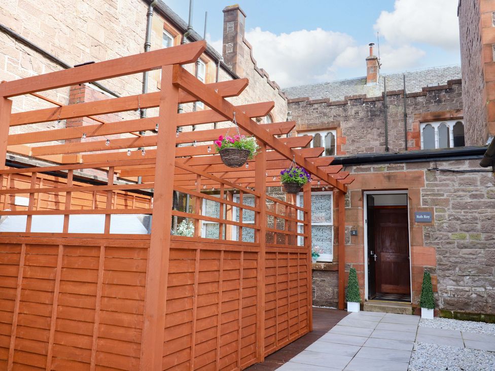 An outdoor area with a wooden pergola and entrance to Rob Roy Apartment in Buchlyvie