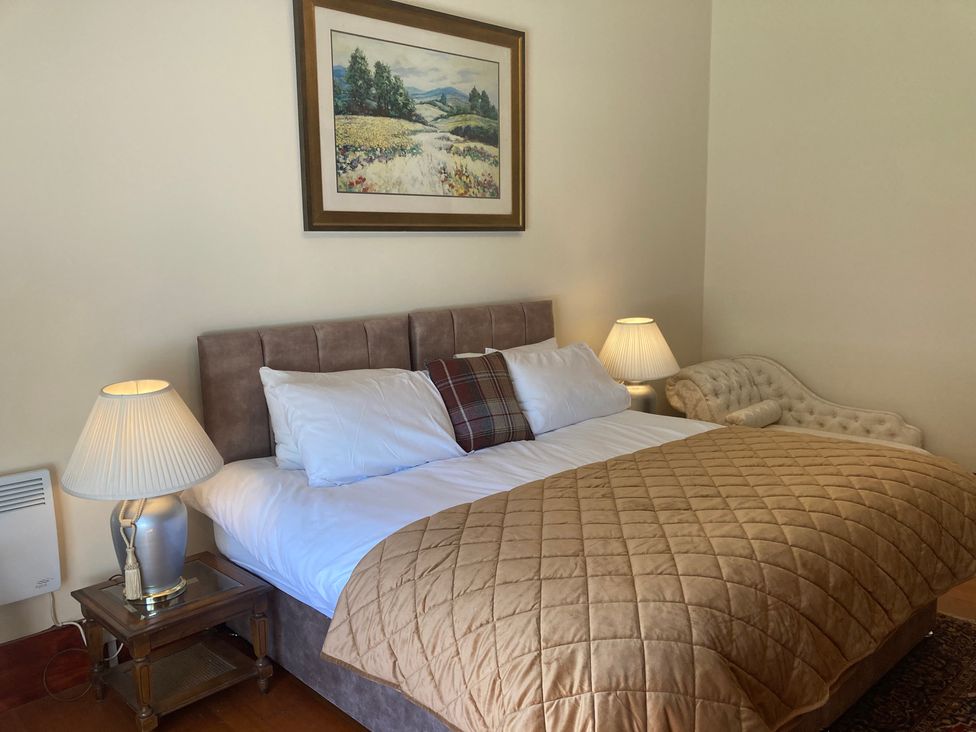 A bedroom with a bed and decorative lamp at Rob Roy Apartment Buchlyvie