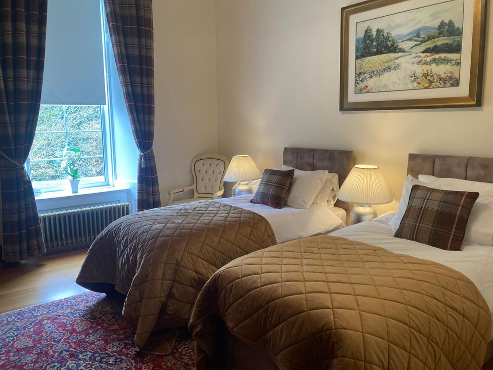 A bedroom with two beds and a chair at Rob Roy Apartment in Buchlyvie