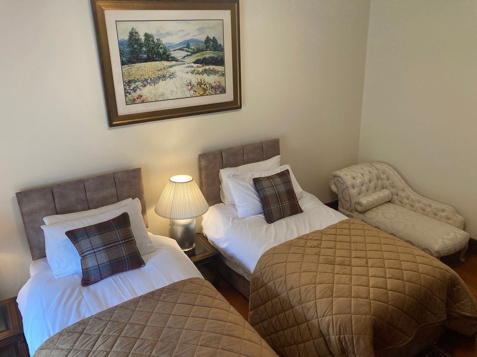 A bedroom with two beds and a sofa at Rob Roy Apartment, Buchlyvie