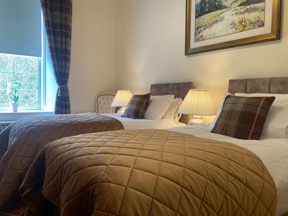 A bedroom with two beds and a window at Rob Roy Apartment in Buchlyvie