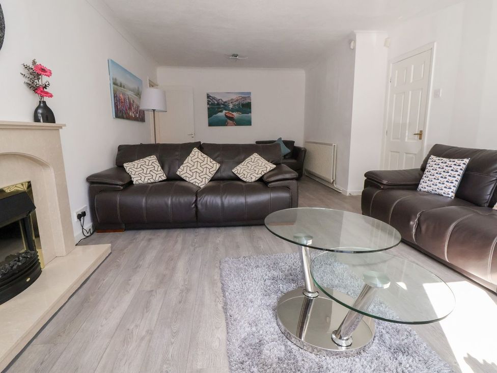 A living room with a sofa, table, and wall art at Castellolwg