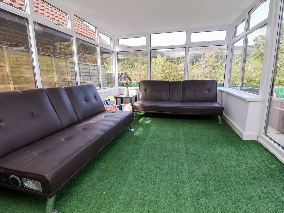 A conservatory with sofas and a table at Castellolwg