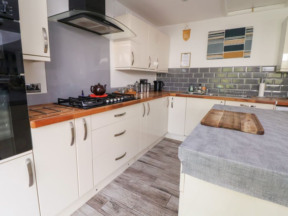 A kitchen with cabinets, stove, and countertop at Castellolwg