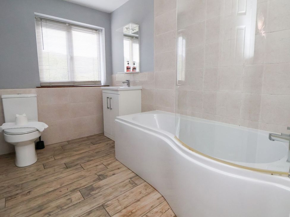 A bathroom featuring a toilet, bathtub, sink, and window at Castellolwg
