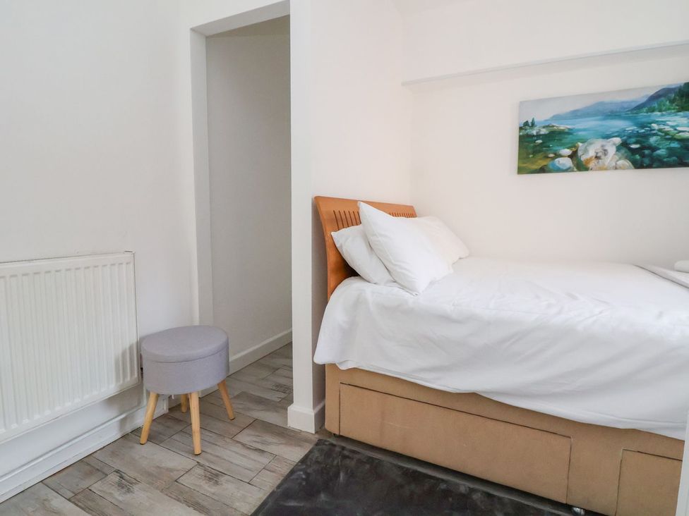 A bedroom with a bed and stool at Castellolwg 