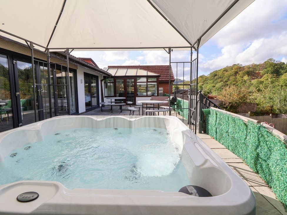 An outdoor patio with a hot tub and seating at Castellolwg