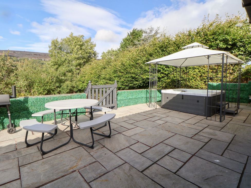 An outdoor area with table, chairs, hot tub, and barbecue at Castellolwg