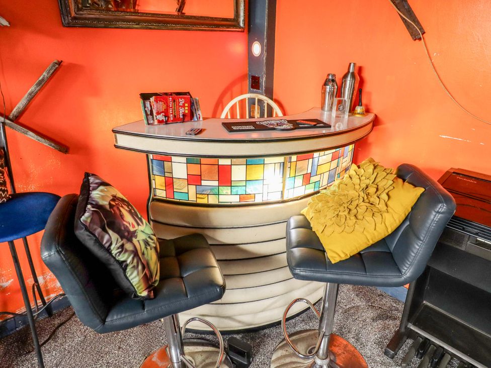 A bar with stools and a mirror at Dormy Cottage in Skegness