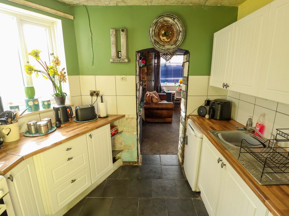A kitchen with white units and a doorway leading to another room at Dormy Cottage in Skegness