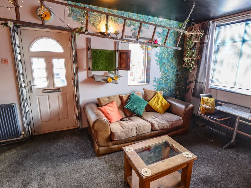 A living room with a sofa, table and chair at Dormy Cottage in Skegness