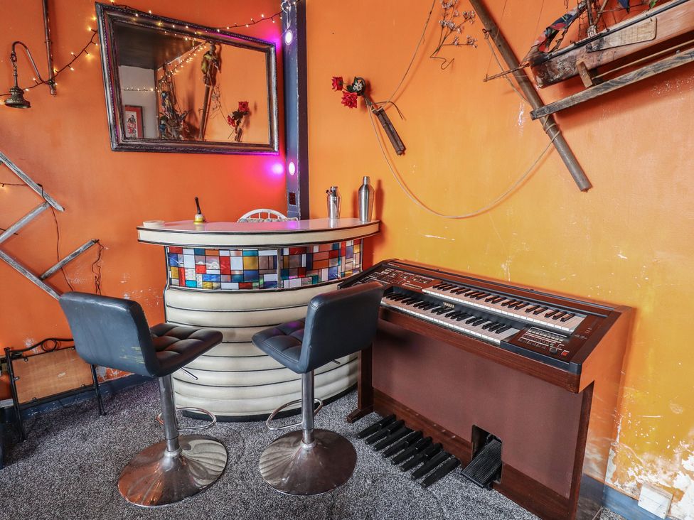 A home bar with a keyboard and stools at Dormy Cottage in Skegness