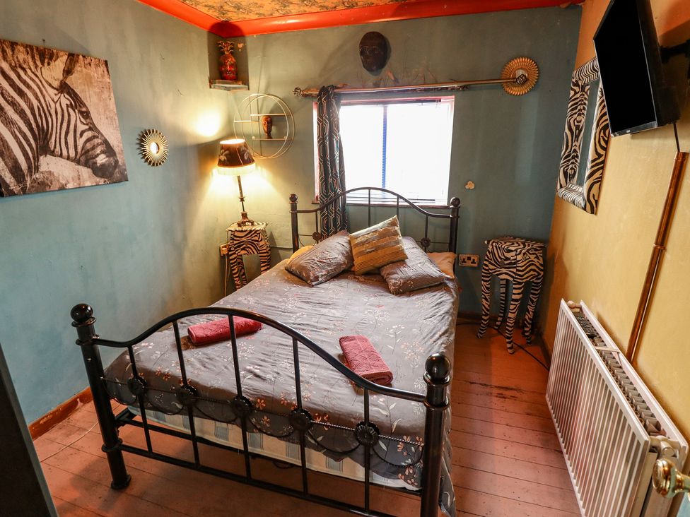 A bedroom with a metal bed and zebra-themed decor at Dormy Cottage in Skegness