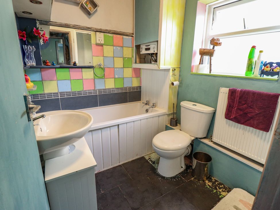 A bathroom with a sink, bathtub, and toilet at Dormy Cottage in Skegness