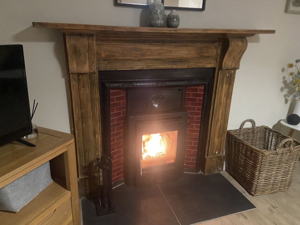 A fireplace with a stove and wooden mantel in the living room at Awelfa, Newport, Pembrokeshire