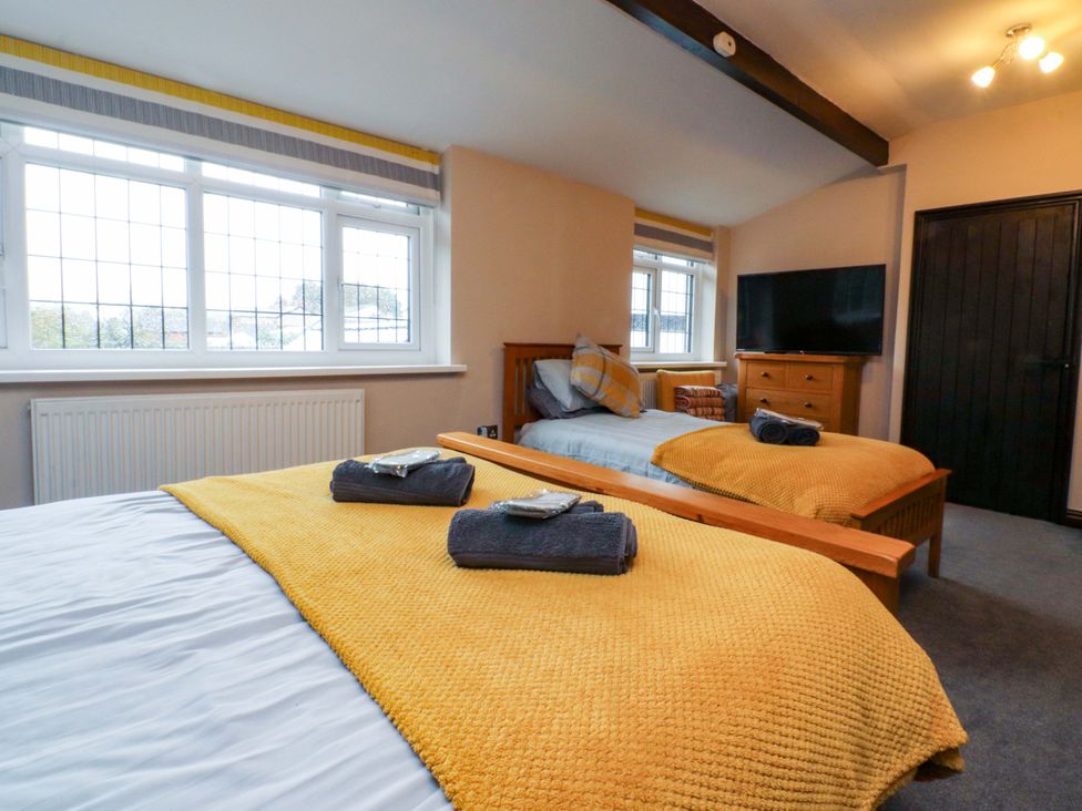 A bedroom with two beds and a television at Mayfield Cottage in Blackpool