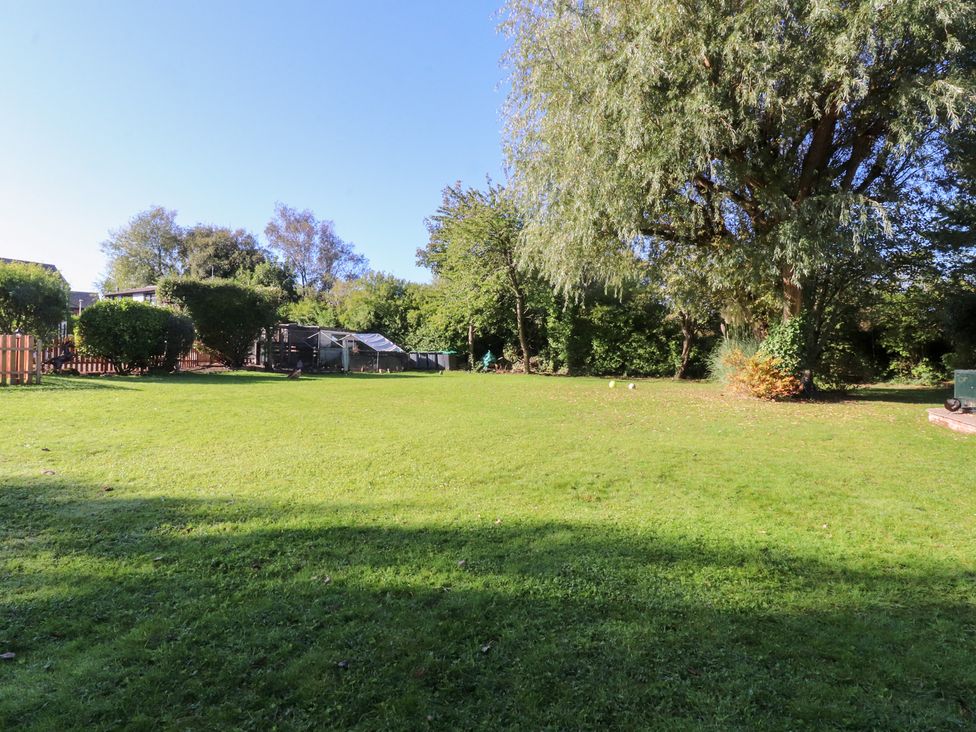 A garden with grass and trees at Mayfield Cottage in Blackpool