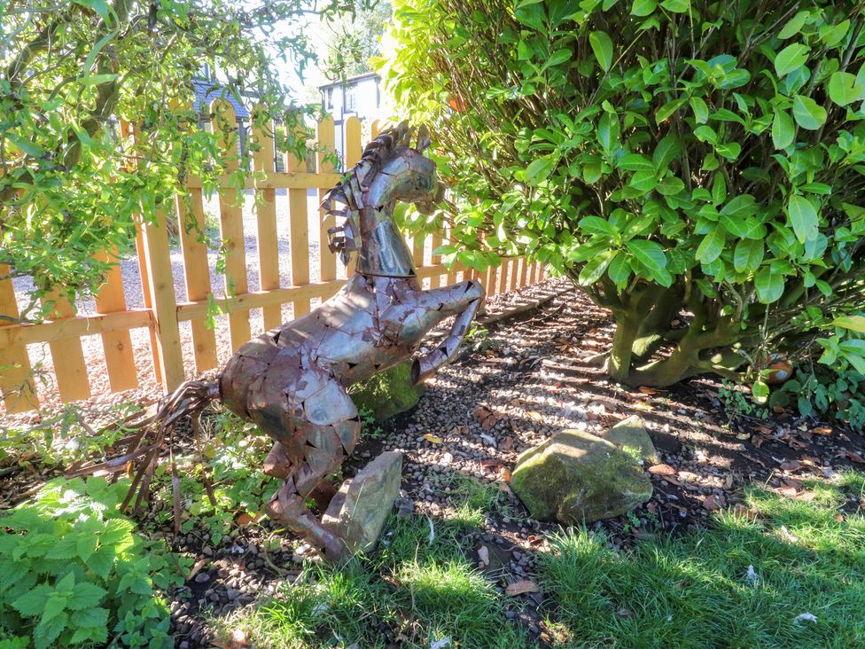 A metal horse sculpture next to a bush in a garden at Mayfield Cottage in Blackpool