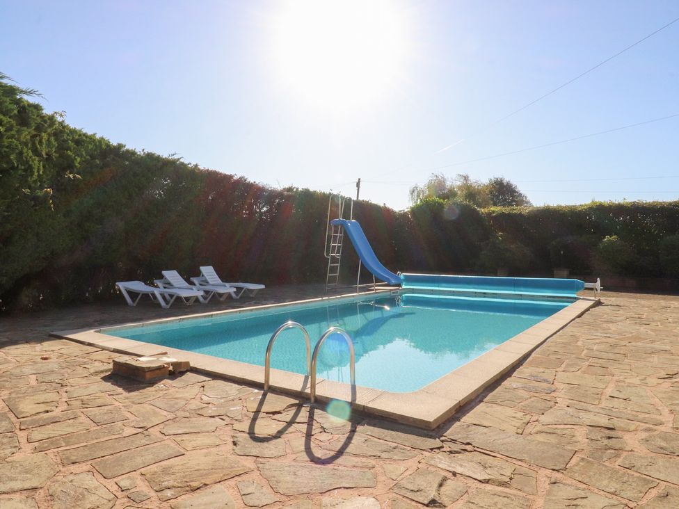 A swimming pool with a slide and deck chairs at Mayfield Cottage in Blackpool