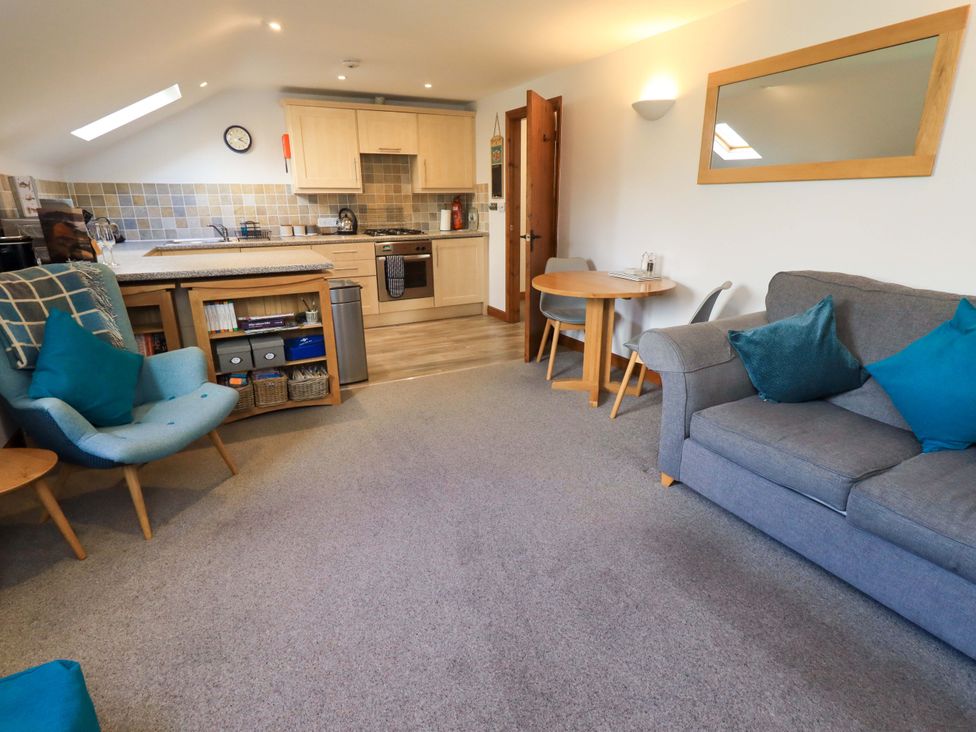 A living room with a kitchen area and furniture at High Dow Crag in Coniston