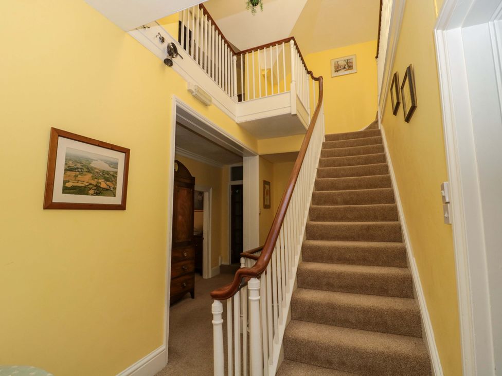 A hallway with stairs and framed pictures at The West Wing 