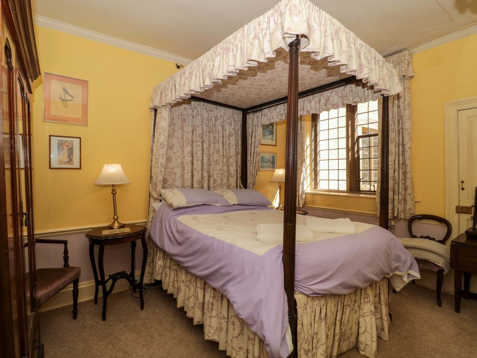 A bedroom with a four-poster bed and lamp at The West Wing 
