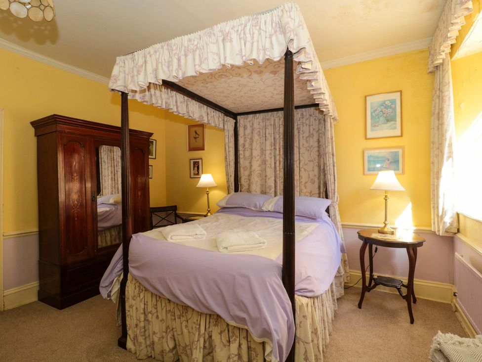 A bedroom with a four-poster bed and a wardrobe at The West Wing 