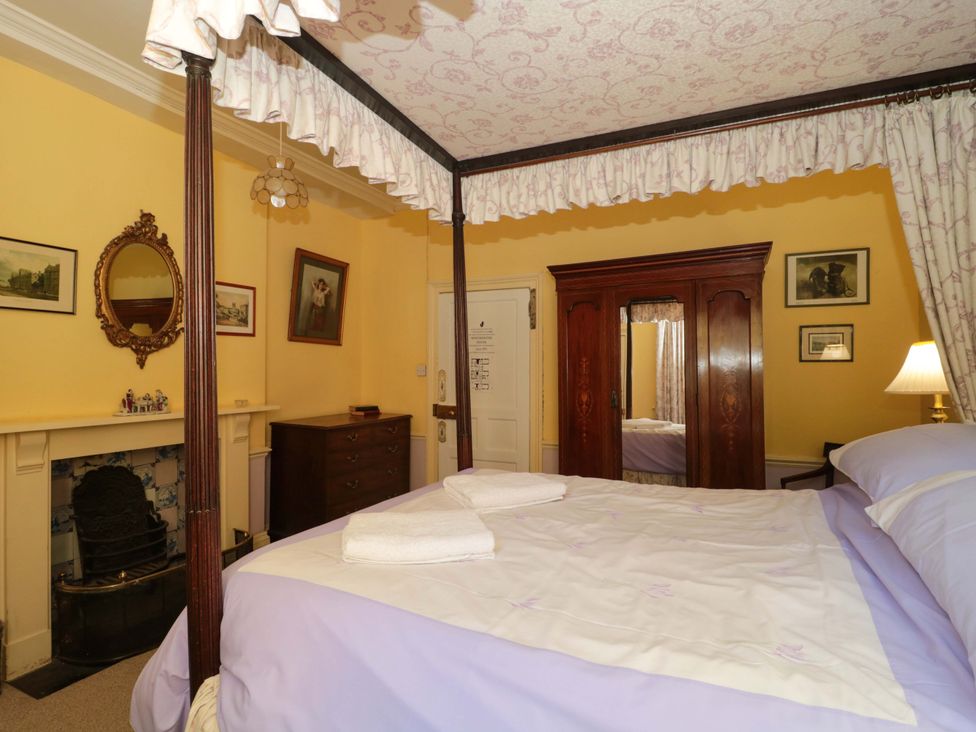 A bedroom with a four-poster bed and wardrobe at The West Wing 