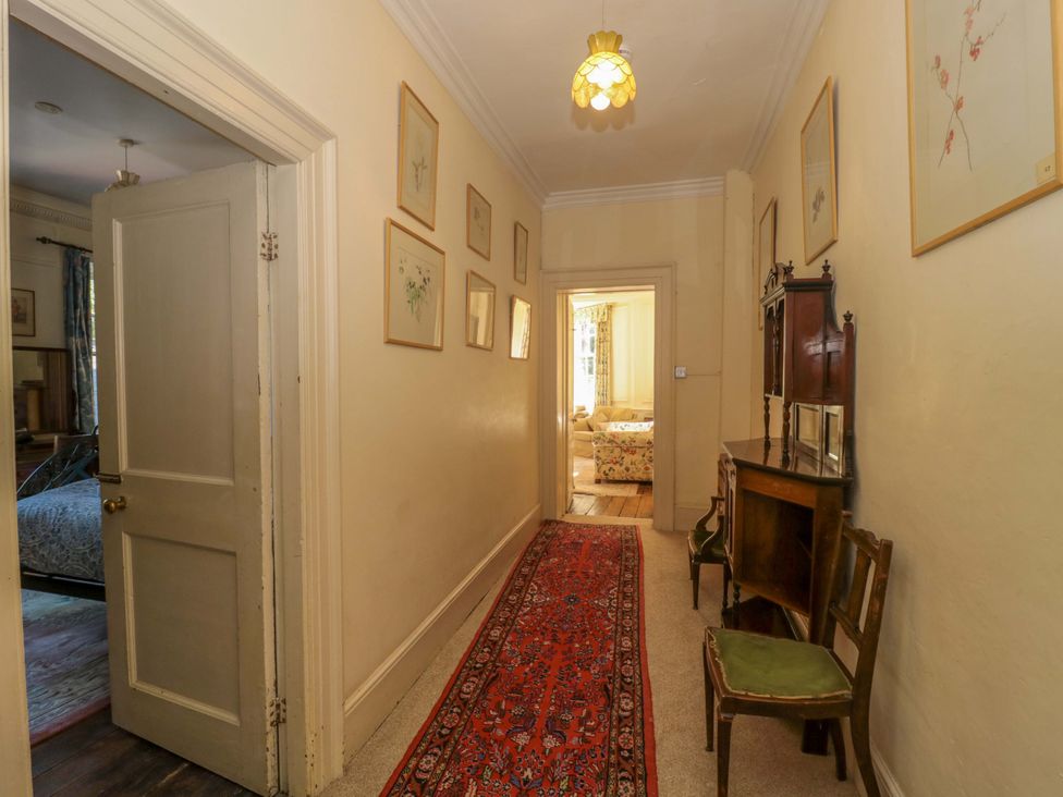 A hallway with a door, chair, and light fixture at The West Wing 