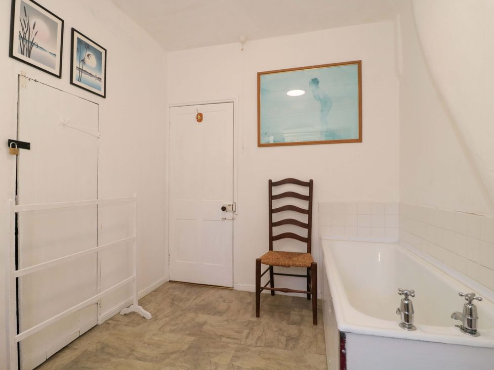 A bathroom with a bathtub and a chair at The West Wing 