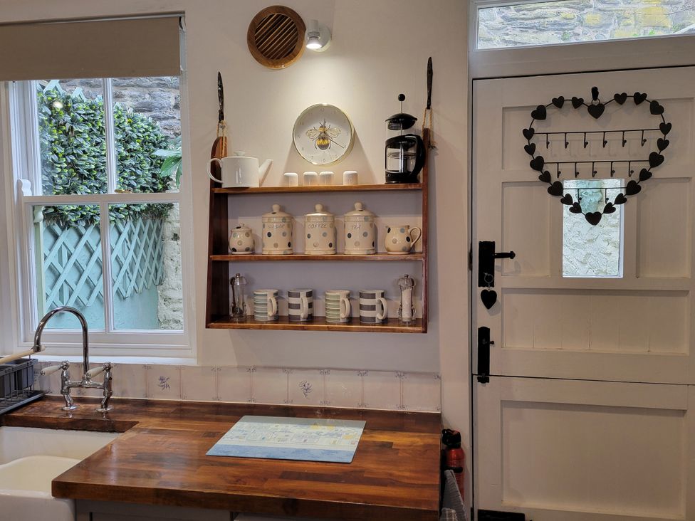 A kitchen with a wooden countertop and wall-mounted shelf at Millgate Cottage in Conwy
