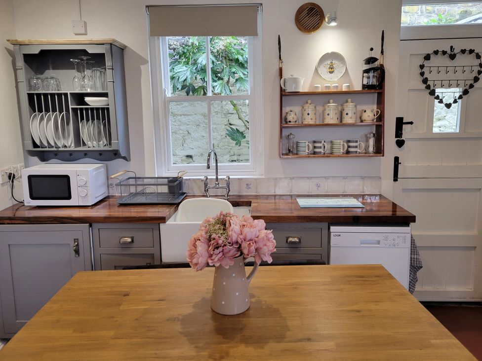 A kitchen featuring a sink, microwave, and wooden countertop at Millgate Cottage in Conwy