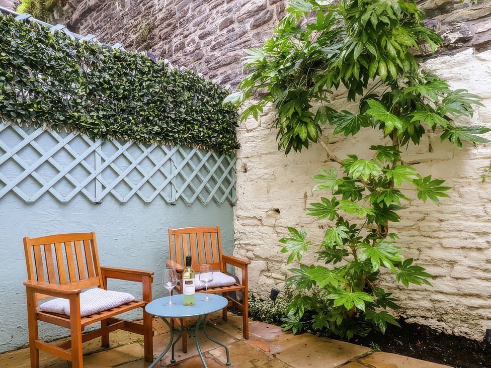 An outdoor area with two wooden chairs and a small table at Millgate Cottage Conwy